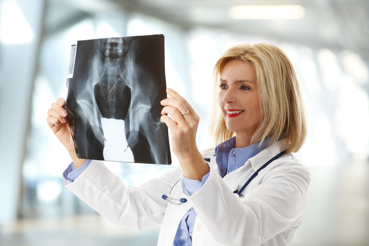 Portrait of middle age female doctor holding hand x-ray image and analyzing it.