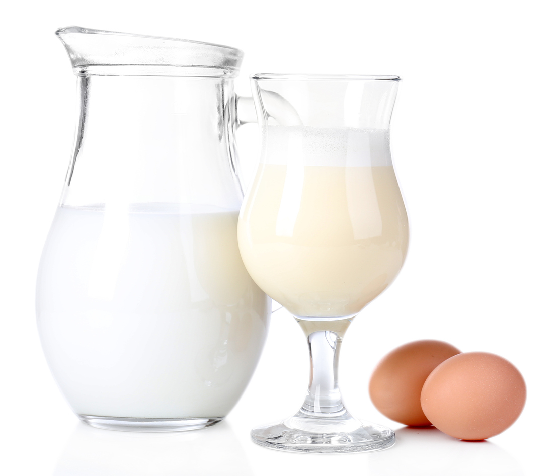 Eggnog with milk and eggs on tablecloth on natural background