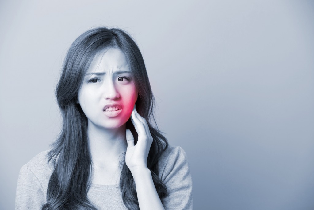 unhappy woman feel pain on her teeth isolated on gray background, asian