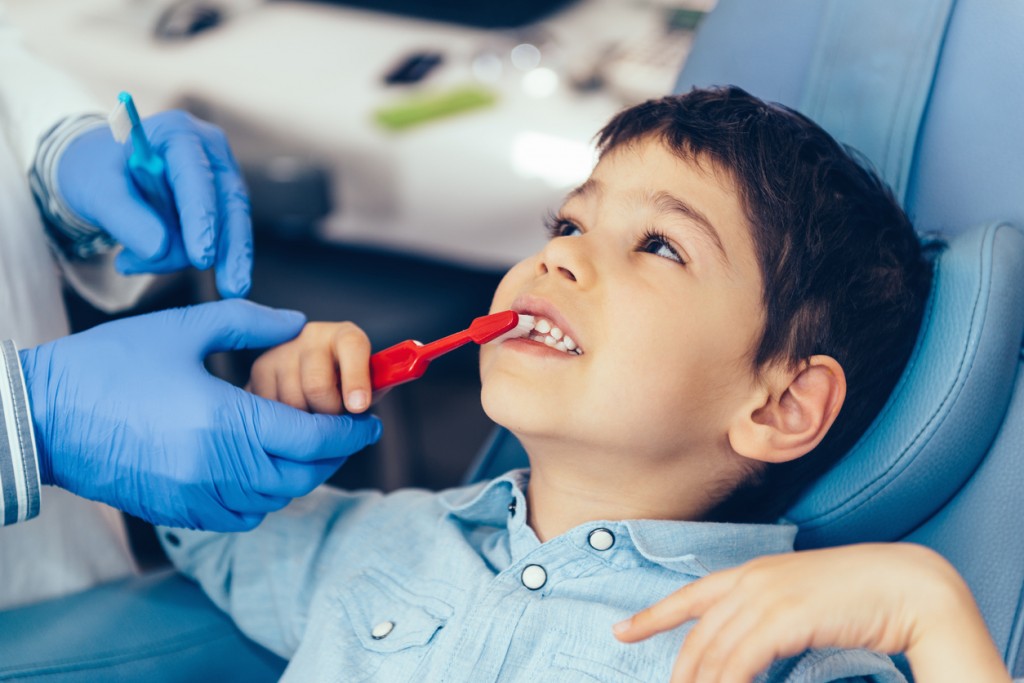Dentist with little boy, practicing brushing teeth