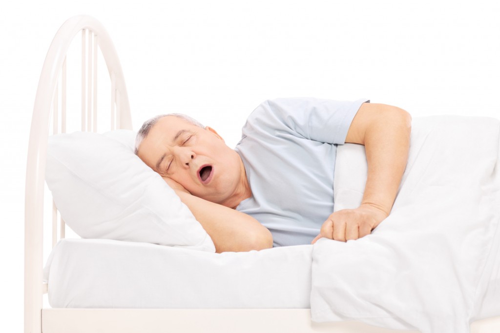 Studio shot of a mature man sleeping in bed isolated on white background