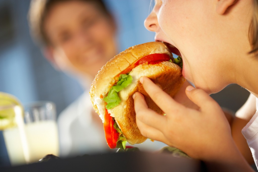 Cropped shot of girl eating big hamburger outdoors