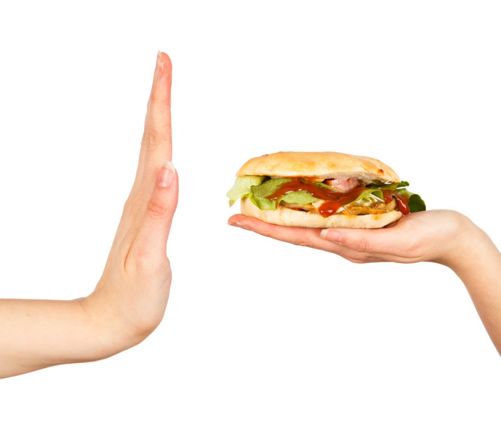 Female hand rejecting the offered unhealthy junk food.