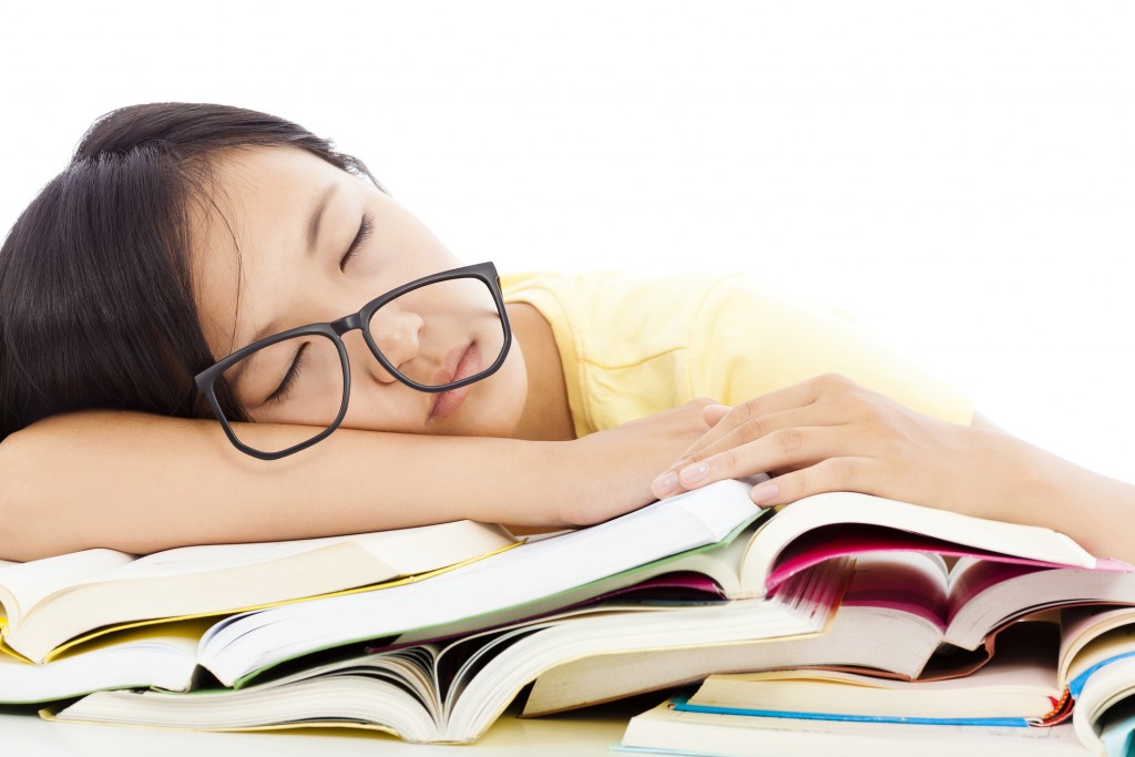 tired student girl with glasses sleeping on the books over white background