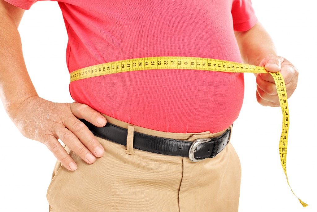 Fat mature man measuring his belly with tape