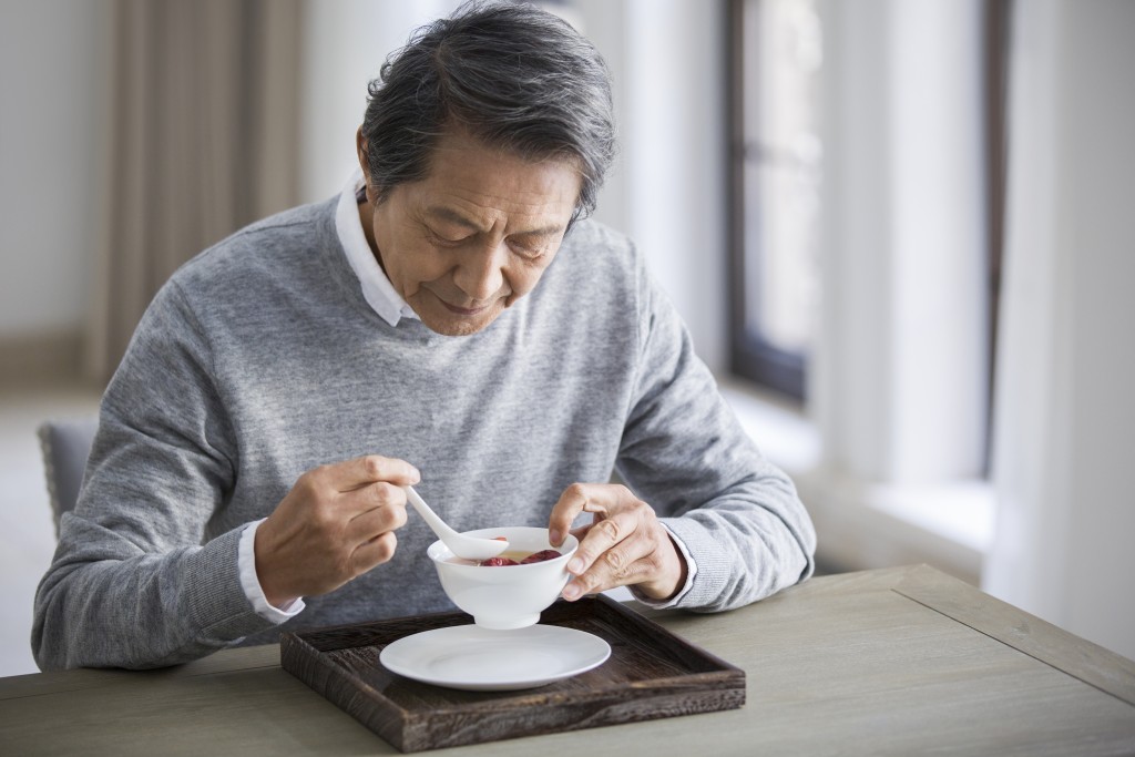 Senior Chinese man eating nutritious porridge