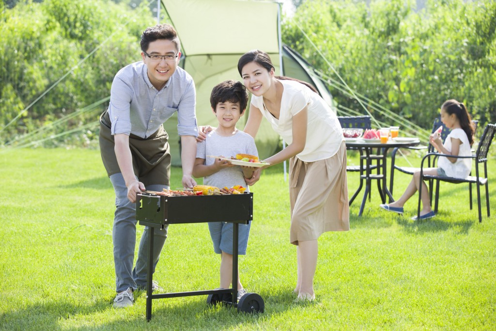 Young Chinese family barbecuing outdoors