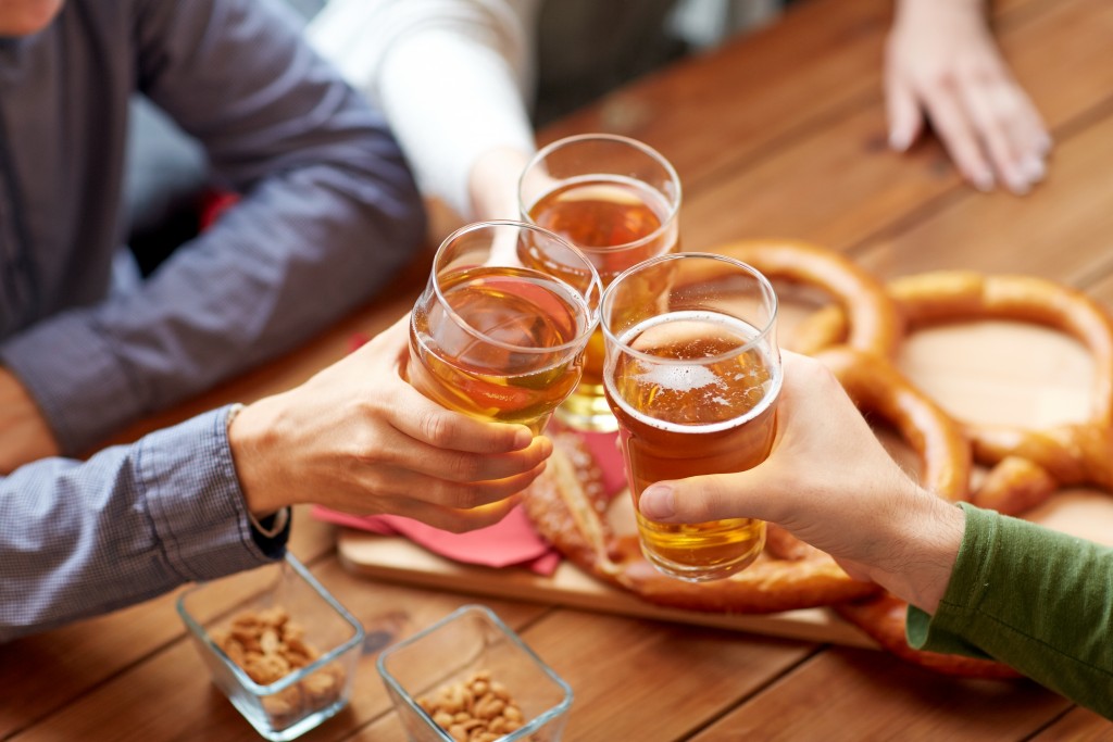close up of hands clinking beer at bar or pub