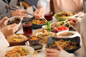 Friends eating tasty Chinese food at table