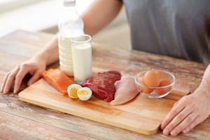 sports nutrition, healthy eating and people concept - close up of male hands with food rich in protein on wooden cutting board