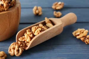 Scoop and bowl with tasty walnuts on color wooden table