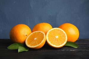 Fresh oranges with leaves on wooden table