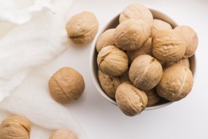 Walnuts in a white ceramic bowl on a white background