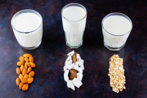 Vegan non dairy alternative milk. Coconut, almond, oat homemade milk on dark background. Different types of non-dairy milk. Healthy drinks concept. Top view. Copy space
