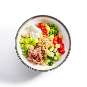 Couscous with beef and cut vegetables. Delicious meal with tofu cheese, cucumber, tomato and avocado. Tasty dish served with sauce, pepper and peas top view. Haute cuisine, food composition