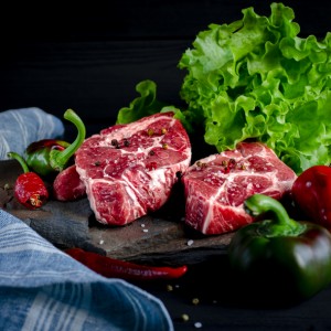 Meat concept. Meat steaks are ready to cook with vegetables lying on the table. Close-up