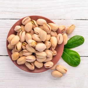 Pistachios nuts on a white wooden background. Healthy snacks. Top view. Free space for text.