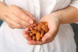 Woman holds tasty almond, close up. Healthy eating