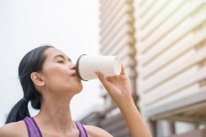 Tan woman drinking coffee after exercise is completed