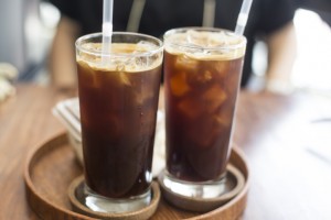 Two iced coffee with glass cups on wooden tray in a coffee shop.