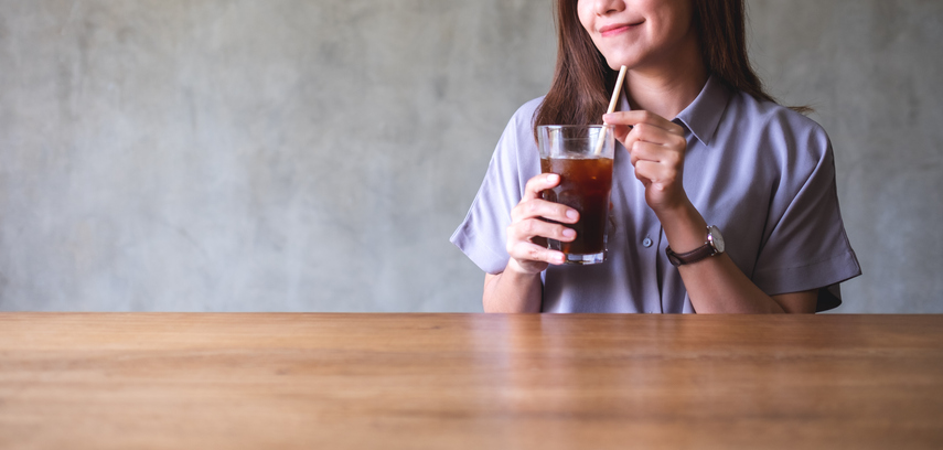 Closeup of a young asian woman holding and looking at a glass of iced coffee