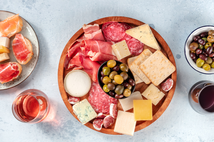 Charcuterie and cheese board with wine and olives, top shot