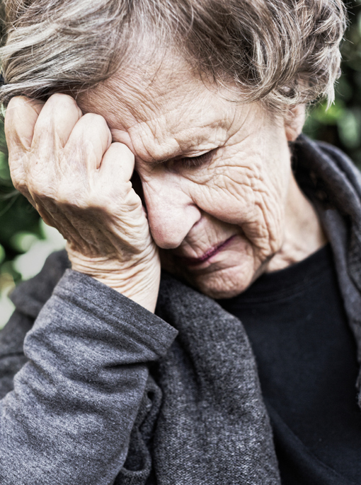 Senior woman overcome by worry, grief or headache rests her head on her hand