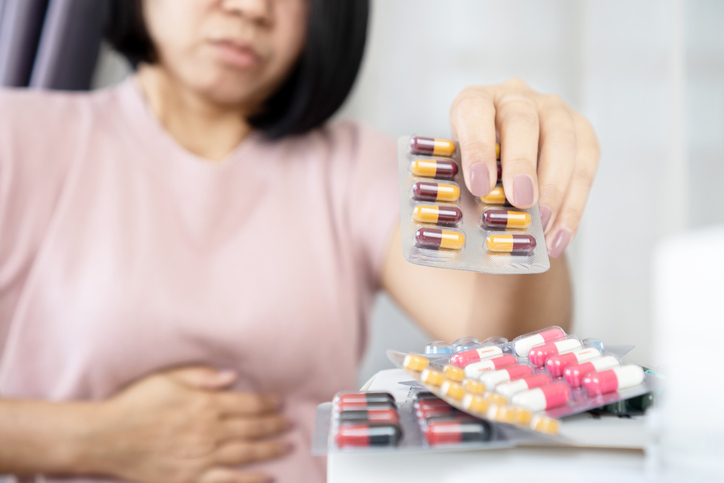 Asian woman taking antibiotics medicine to treat stomachache caused by (irritable bowel syndrome
