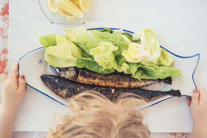 Girl eats grilled fish